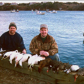 Sea duck hunters on shore with bagged birds
